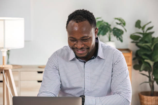 istock Focused african businessman holding documents looking at laptop doing research. business financial analyst concept 1475723111