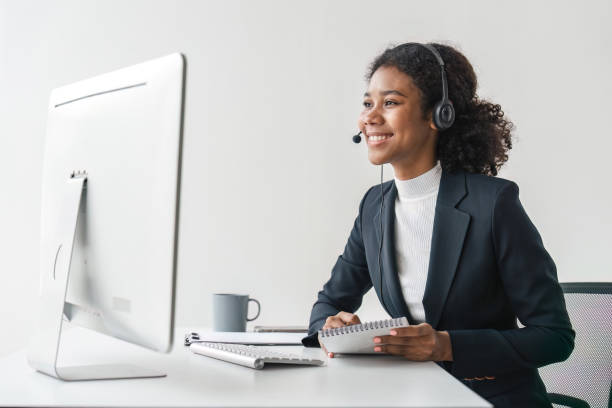 Portrait of happy smiling female customer support phone operator at workplace. Smiling beautiful African American woman working in call center