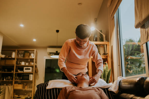 Therapy massage with senior massage therapist. Senior Thai massage therapist massaging her customer, migraine therapy with relax. chinese herbal medicine stock pictures, royalty-free photos & images