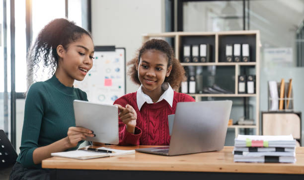 Young group of diverse students studying together using laptop at home. College multiracial people working on university group assignment homework project in modern apartment