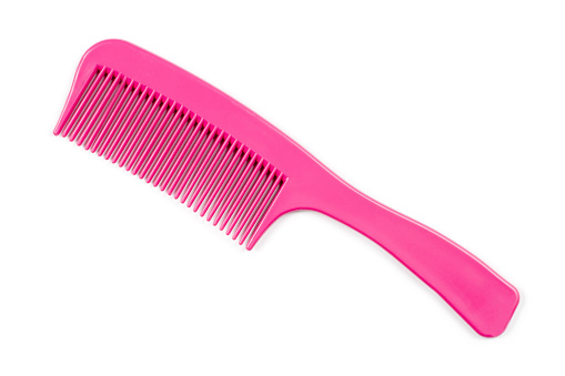 Pink comb with a handle on a white background. Simple plastic comb.