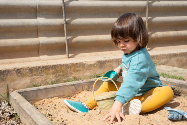 istock Concentrated 2 year old girl playing in a sandbox. 1475750404