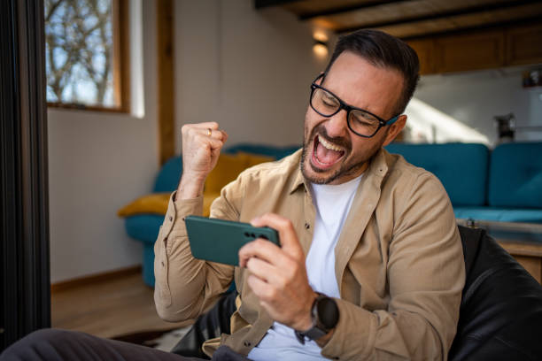 istock Smiling middle-aged man playing video games on his smartphone 1475754675
