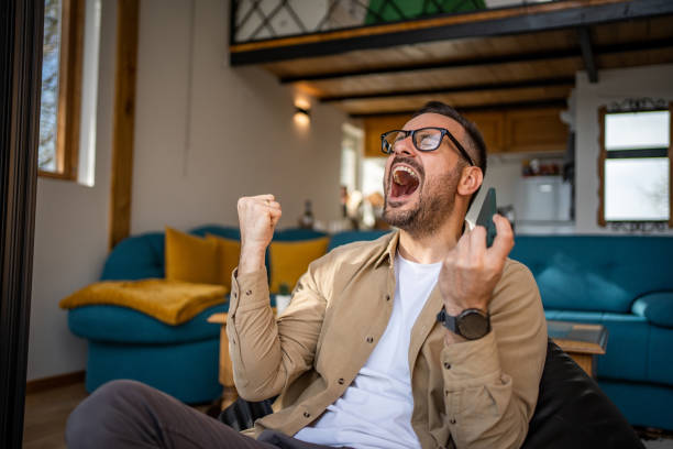 istock Smiling middle-aged man playing video games on his smartphone 1475754700