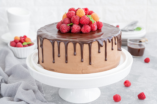 Layered honey chocolate cake with glaze and fresh raspberries on top. Delicious chocolate cake