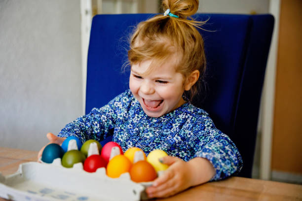 istock Excited little toddler girl coloring eggs for Easter. Child looking surprised at colored egg hoarding and celebrating catholic and christian holiday with family. Cute kid helping to color, indoors. 1475762162