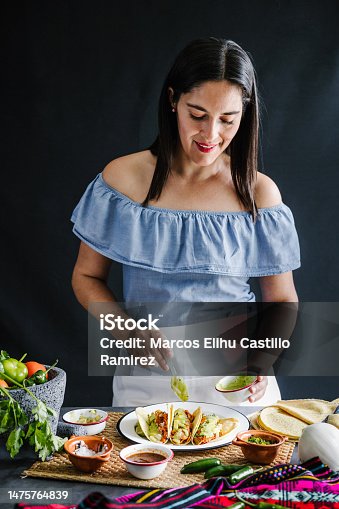 istock Mexican woman cooking tacos al pastor and eating traditional food in Mexico Latin America 1475764839