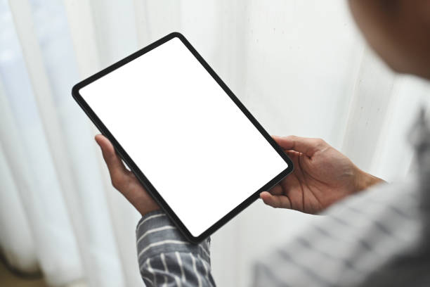 istock Closeup over shoulder view man holding digital tablet standing in bright office. Blank screen for your advertising text message. 1475764843