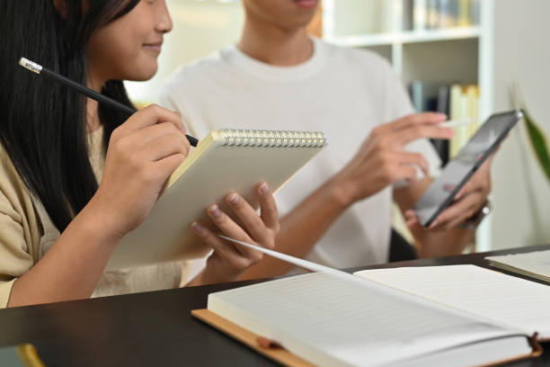 tutor che indica il tablet digitale, dando lezioni educative private a un'adolescente concentrata. homeschooling e concetto di educazione. - home schooling foto e immagini stock