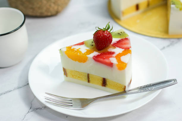 istock Pieces of Homemade Fruit Pudding served on white plate, fork on table. soft white pudding with ingredients of strawberries, oranges, kiwi. Selective focus. 1475766660