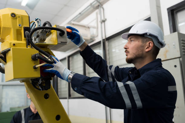 istock Male engineer worker using screwdriver maintenance automatic welding robotic arm machine. Male technician worker checking, repair automatic welding robot arm machine 1475769767