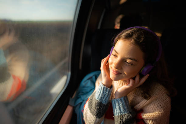 ragazza adolescente che ascolta una musica in cuffia mentre viaggia in treno - music listening child smiling foto e immagini stock