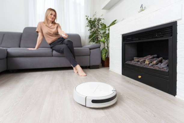 istock Robotic vacuum cleaner cleaning the room while woman resting on sofa 1475775462