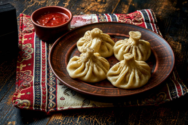 Khinkali with meat filling in a plate. Georgian dumplings in a composition with sauce and vegetables stock photo