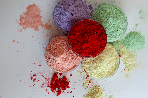 Holi powder color in transparent bowls isolated on the colorful background. Colorful Indian festival Holi celebration