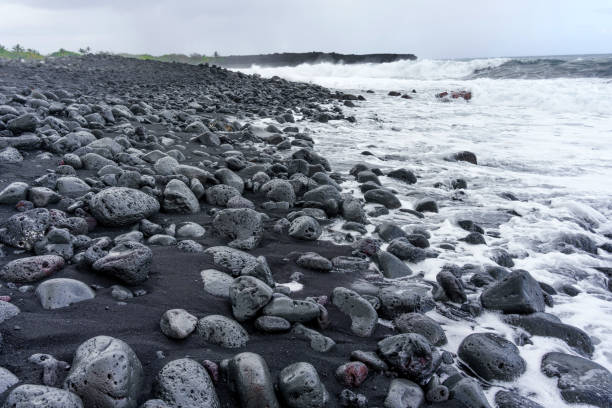 Bunch of wet volcanic stones on the Hawaiian coast covered with white foam from the tidal wave.