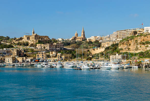 The port of Mġarr on the island of Gozo, Malta. Beautiful city on the cliffs and hills on the background on sunny spring day. The port of Mġarr on the island of Gozo, Malta. Beautiful city on the cliffs and hills on the background on sunny spring day. mgarr malta island gozo cityscape with harbor stock pictures, royalty-free photos & images