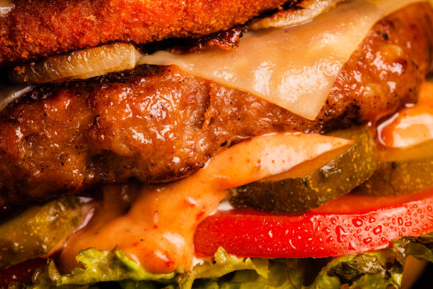 Double burger with bacon grilled yellow cheese onions tomatoes cucumber and lettuce. Abstract fast food background. stock photo
