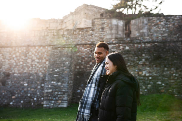 Man and woman walking in front of an old stone wall. stock photo