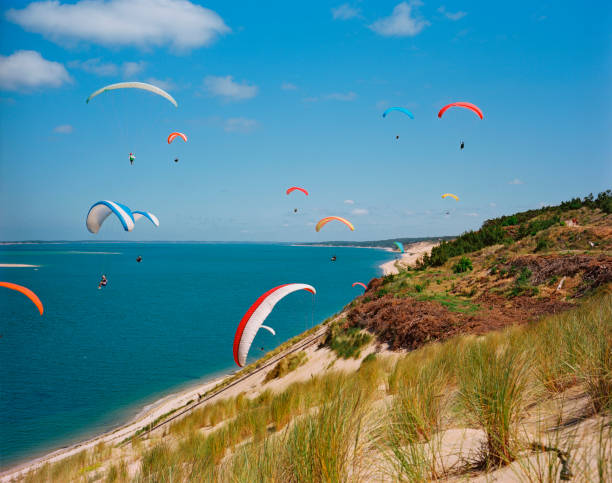 Paragliding on the Dune Du Pilat Paragliding on the sand dune of Pilat near Arcachon. Photo taken analog with medium format camera. airborne sport stock pictures, royalty-free photos & images