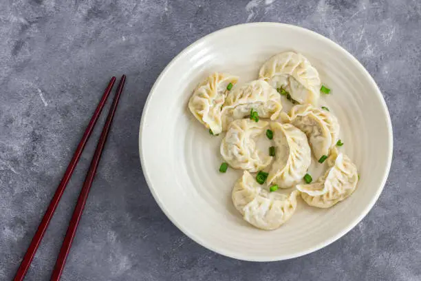 Photo of Chicken Dumplings in a Plate with Chopsticks Directly Above Photo