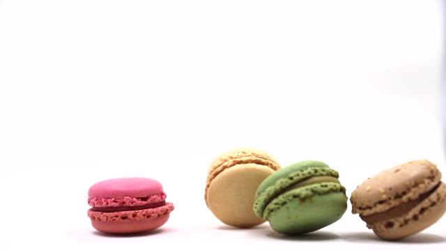 Colored macarons fall down at white background