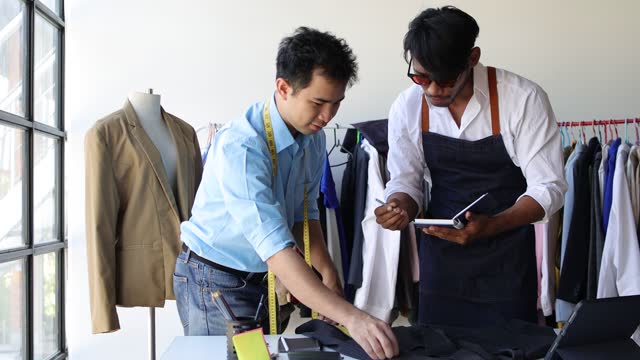 Two male fashion designers working in a design studio are designing clothes.