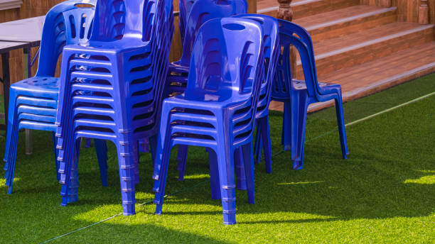 istock Group of blue plastic chairs and foldable table on green artificial turf outside of building for outdoors event 1475789403