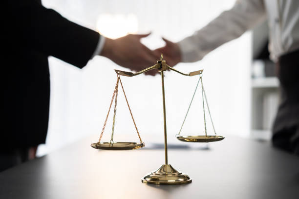Focus law symbols on blur background of lawyer colleagues handshake. Equilibrium stock photo