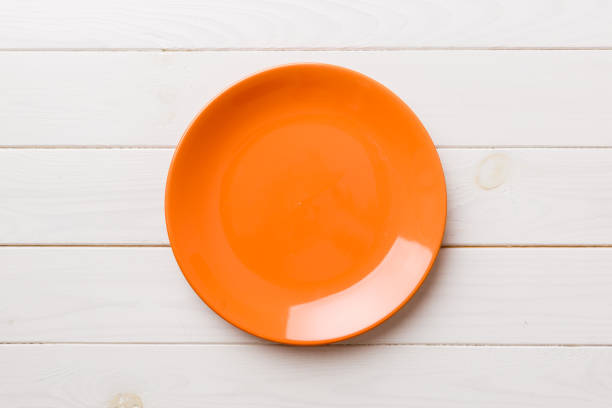 istock Top view of empty orange plate on wooden background. Empty space for your design 1475794848