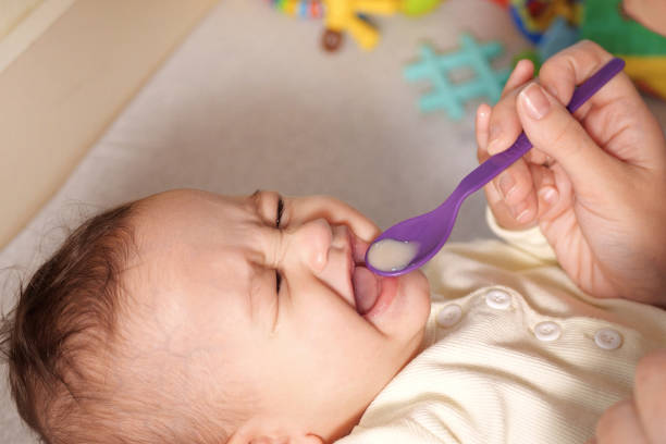 Newborn child drinking water or medicine cough syrup with spoon, close up. little baby drink medical syrup stock photo