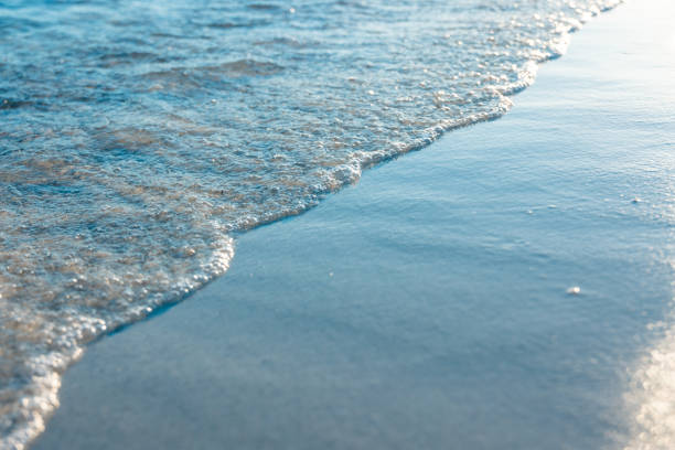 Soft blue ocean wave on clean sandy beach, summer concept