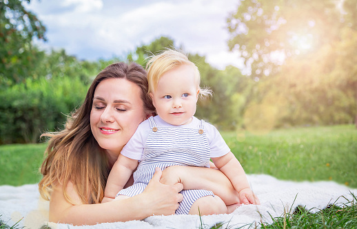 Healthy child (kid) with mother enjoying a sunny summer day at the park. Caucasians happy baby (boy) in the casuals clothing. Healthy lifestyle, happy childhood, Mother's Day concept. Copy space.