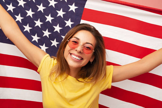 istock Delighted young woman smiling and raising US flag 1475800747