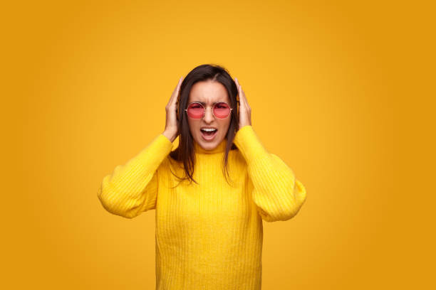 Displeased woman covering ears from noise stock photo