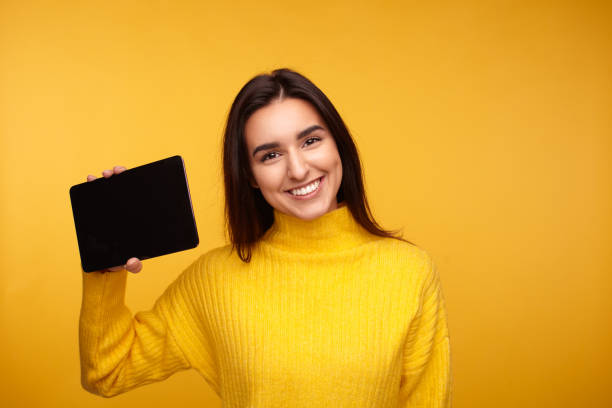 istock Happy brunette showing blank tablet to camera 1475804357