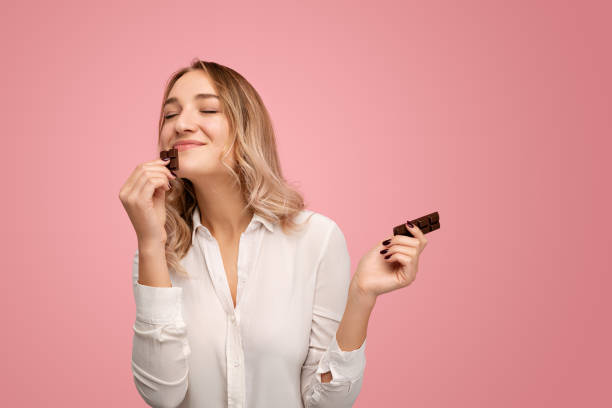 istock Happy young lady smelling yummy chocolate bar in studio 1475804467