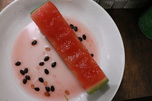 Leftovers after eating watermelon, a summer specialty. On a plate are watermelon skins, seeds and red juice. It was very delicious.