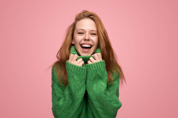 istock Delighted young lady in sweater laughing at camera in pink studio 1475805805