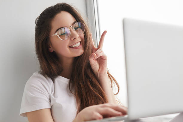 istock Smiling lady showing V sign during online lesson at home 1475805956