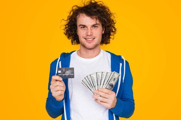 istock Young man showing credit card and money 1475807965
