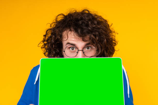 istock Young guy covering mouth with netbook with green screen 1475807977