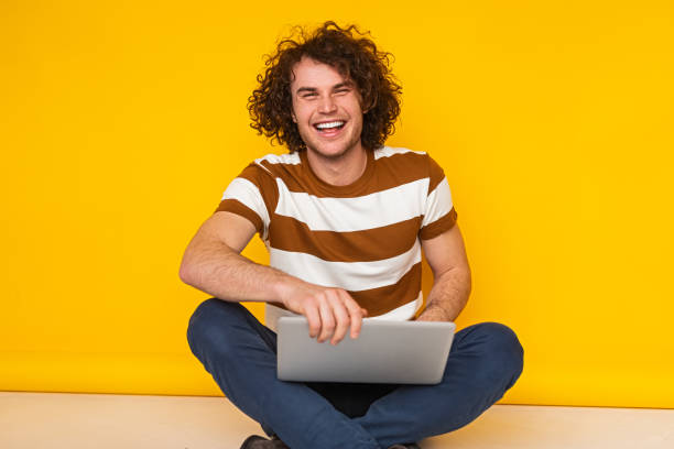 istock Happy young self employed man browsing laptop and smiling in studio 1475807993