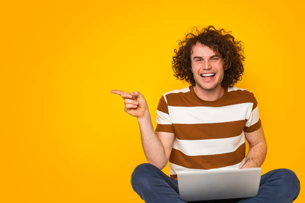 istock Cheerful self employed man smiling and pointing aside during online work 1475808004