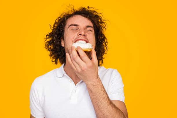 Young guy enjoying yummy doughnut with closed eyes