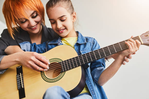 istock Female tutor teaching student to play guitar 1475808094