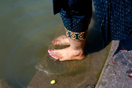 Women washing her feet in scared pond in temple outdoor in nature