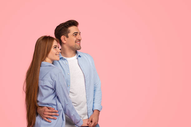 istock Happy beloved couple hugging and smiling in pink studio 1475812933