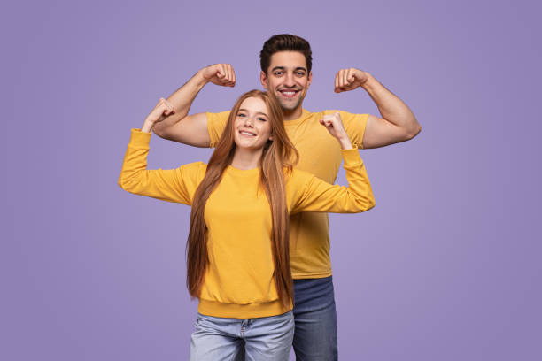 istock Excited young couple showing biceps in purple studio 1475813131
