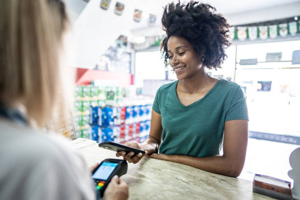 istock Young woman paying with mobile phone at a paint store 1475817432